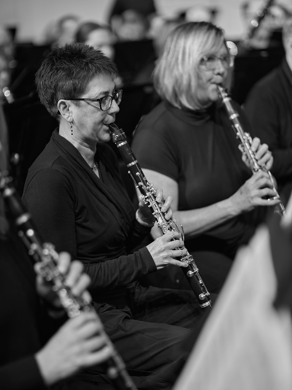 A black and white image of three women playing clarinet in black concert attire.